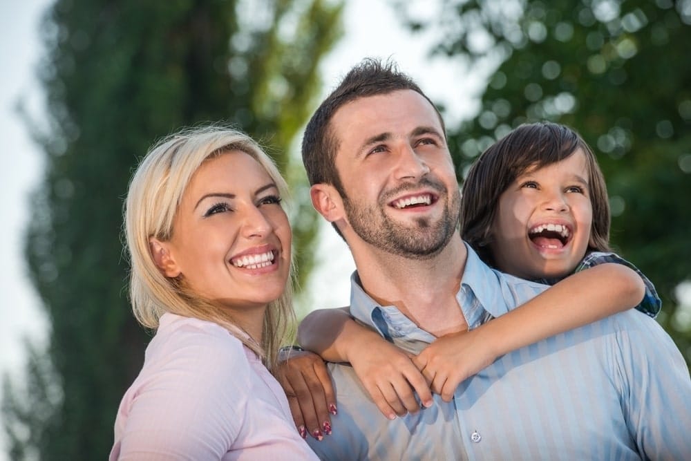 Smiling parents with kid outdoors looking up